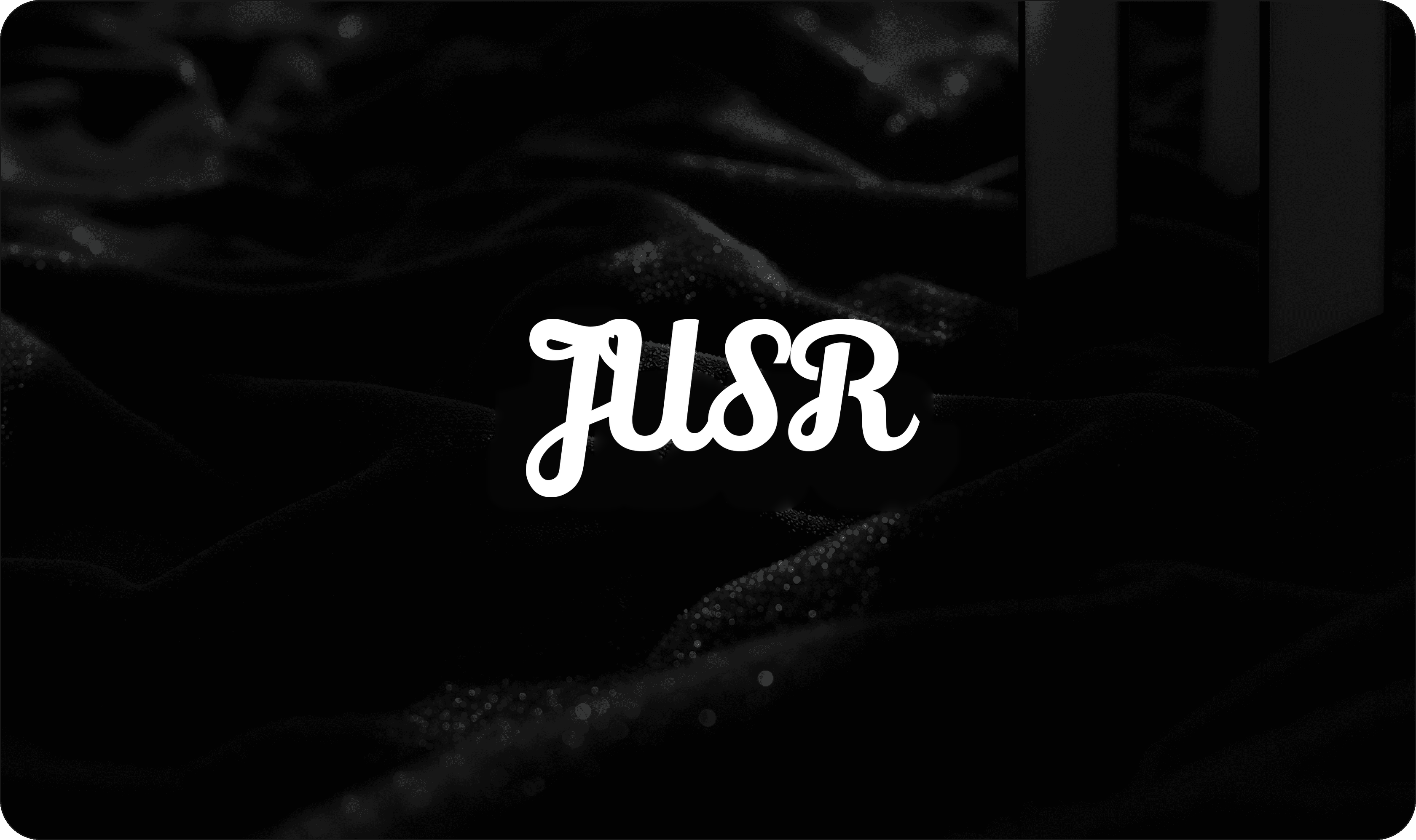 JUSR logo on dark silk fabric background — company announcement